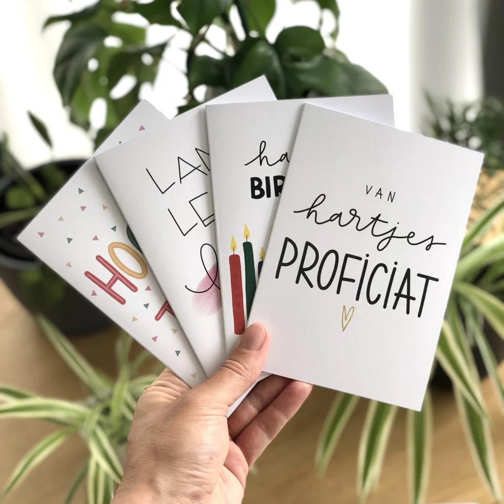 Een hand met vier handgeletterde wenskaartjes van By Birthe